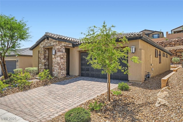 243 Sun Glaze Ave, Henderson, NV 89011 - view of front of home featuring driveway, an attached garage, a tile roof, stucco siding, and stone siding