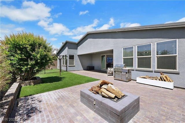 1609 Dream Canyon Ave, North Las Vegas, NV 89084 - back of house featuring fence, a yard, stucco siding, a patio area, and an outdoor fire pit