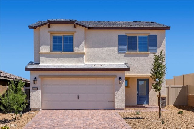 view of front of house featuring fence, a tiled roof, decorative driveway, a garage, and stucco siding