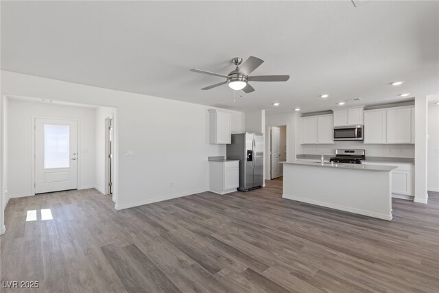 kitchen featuring open floor plan, baseboards, white cabinets, appliances with stainless steel finishes, and wood finished floors