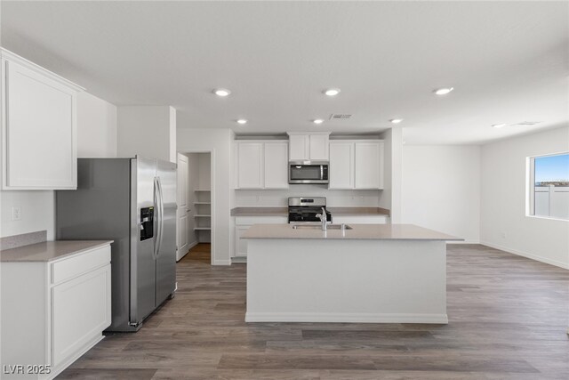 kitchen with white cabinetry, a sink, appliances with stainless steel finishes, and wood finished floors