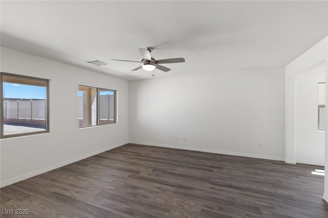 unfurnished room with a ceiling fan, visible vents, baseboards, and dark wood finished floors
