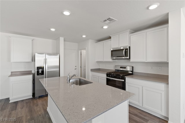 kitchen featuring stainless steel appliances, a sink, visible vents, white cabinets, and a kitchen island with sink