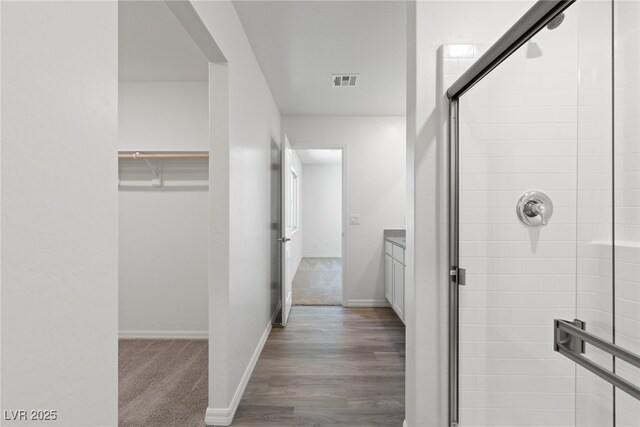full bath featuring wood finished floors, a shower stall, baseboards, and visible vents
