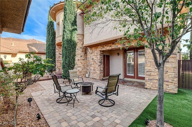 view of patio featuring french doors, fence, and a fire pit