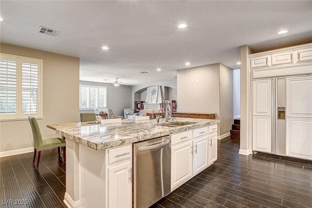 kitchen with baseboards, a center island with sink, a sink, and dishwasher