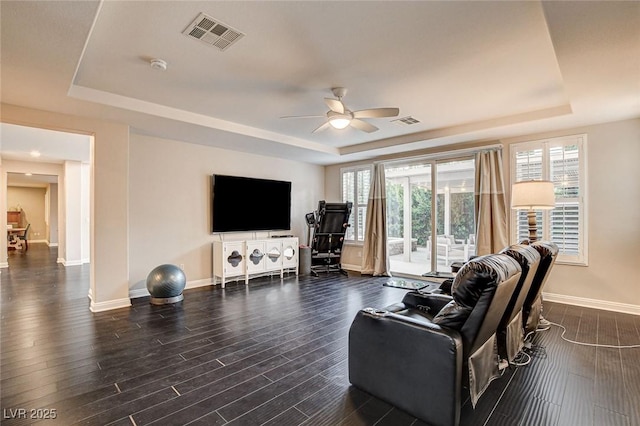 living room featuring a raised ceiling, baseboards, ceiling fan, and visible vents