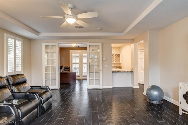 living area featuring visible vents, a tray ceiling, french doors, a ceiling fan, and dark wood finished floors