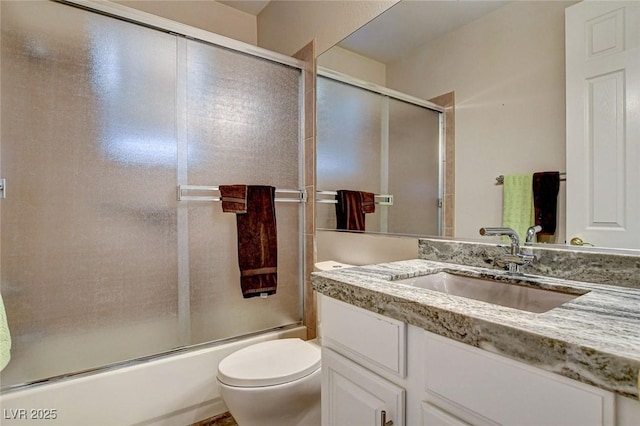 bathroom featuring vanity, bath / shower combo with glass door, and toilet