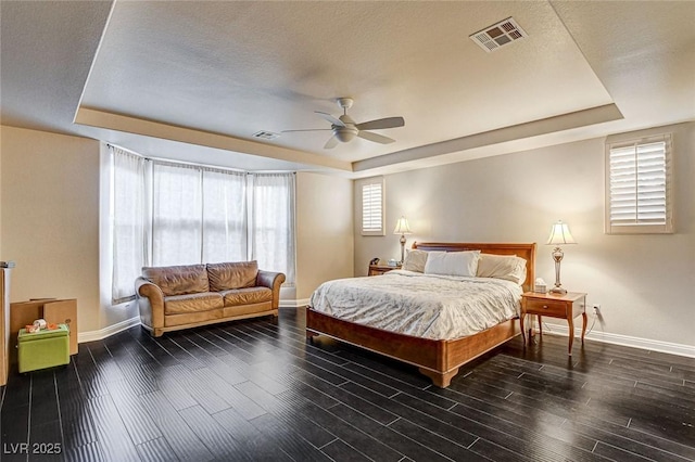 bedroom with a tray ceiling, visible vents, and baseboards