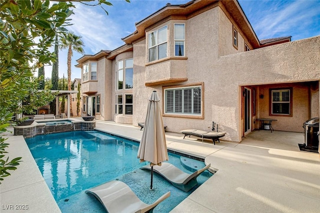 rear view of house with a patio area, stucco siding, and a pool with connected hot tub