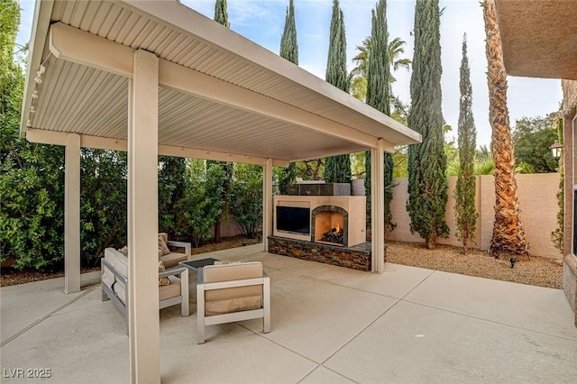 view of patio / terrace with a fenced backyard and an outdoor living space with a fireplace