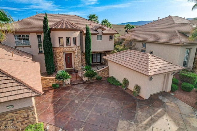 view of front facade with a garage, stone siding, stucco siding, a tiled roof, and concrete driveway