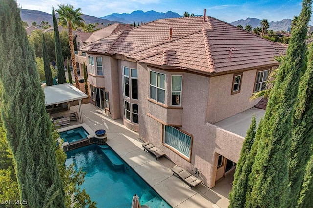 view of swimming pool featuring a patio, a pool with connected hot tub, and a mountain view