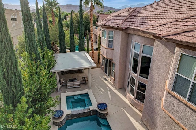 outdoor pool featuring a patio, an in ground hot tub, and a mountain view