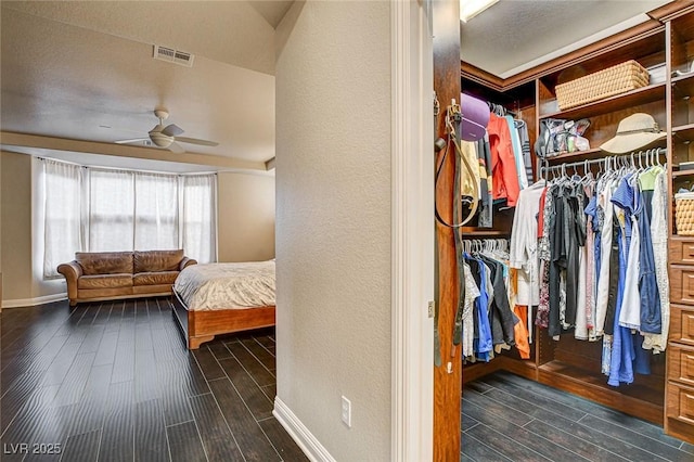 interior space with a ceiling fan, dark wood-type flooring, and visible vents