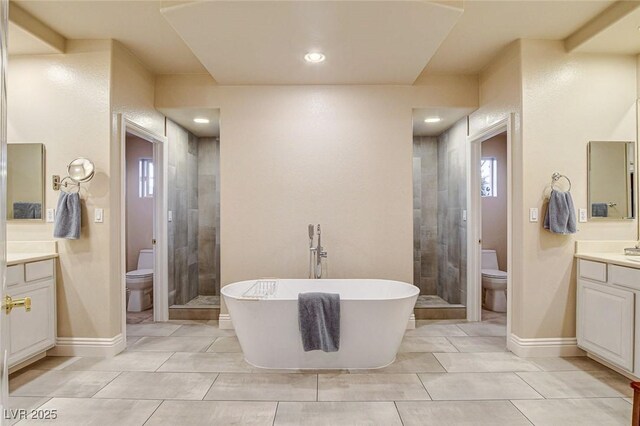 bathroom featuring vanity, toilet, a freestanding tub, and a stall shower