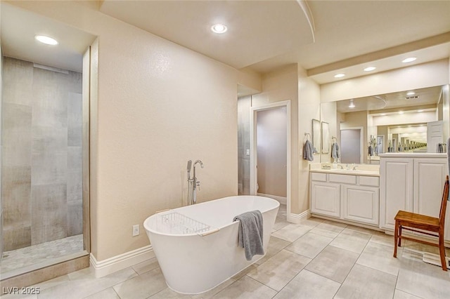 bathroom with recessed lighting, a freestanding bath, a tile shower, and vanity