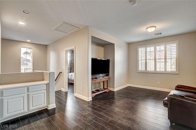 living area with baseboards, visible vents, dark wood-style floors, and a wealth of natural light