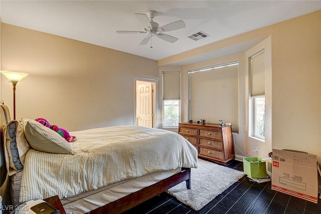 bedroom with dark wood-style floors, baseboards, visible vents, and multiple windows