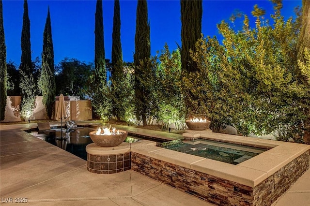 view of patio / terrace with an outdoor fire pit and an in ground hot tub