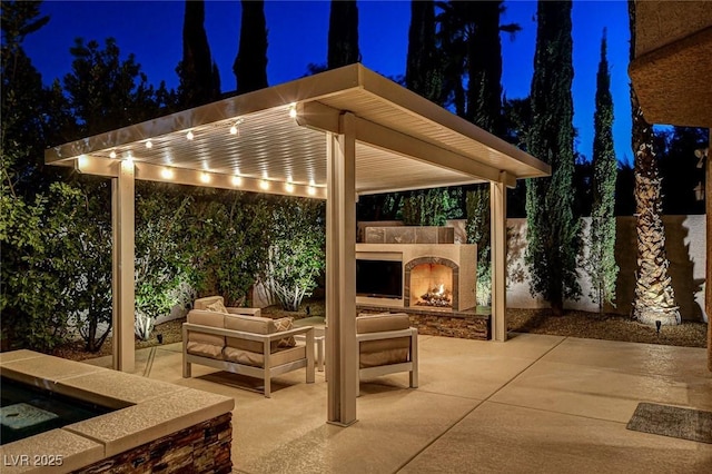 patio at night with an outdoor living space with a fireplace