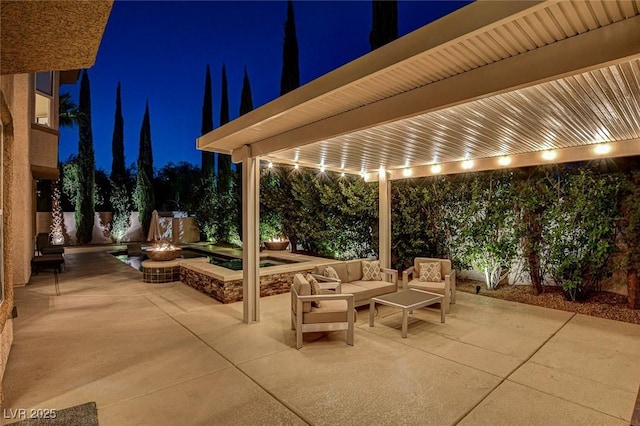 patio at night with an outdoor living space with a fire pit