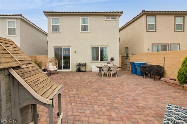 rear view of property featuring stucco siding, a patio, fence, and outdoor dining area