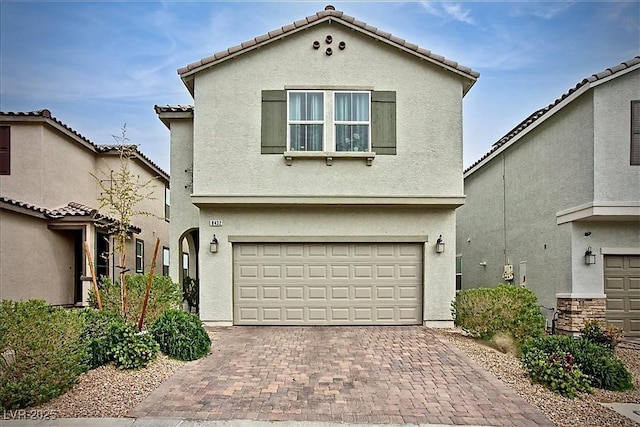 mediterranean / spanish home with decorative driveway, a garage, stucco siding, and a tile roof