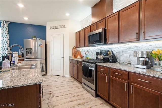 kitchen with stainless steel appliances, a sink, backsplash, light wood-style flooring, and recessed lighting
