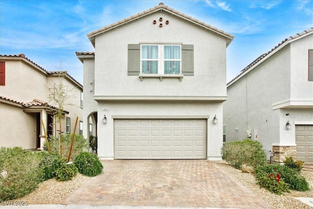 mediterranean / spanish-style home with a garage, decorative driveway, and stucco siding