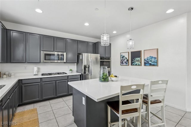 kitchen with stainless steel appliances, light tile patterned floors, light countertops, and a kitchen island