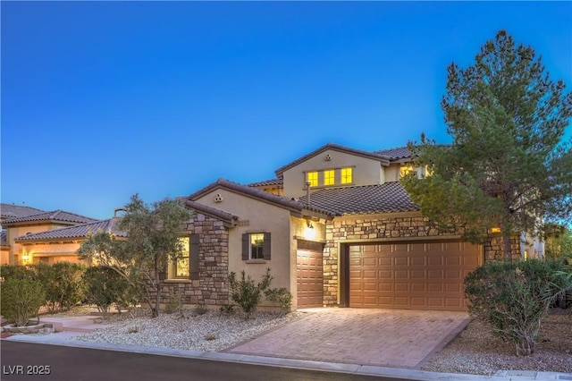 79 Rezzonico Dr, Henderson, NV 89011 - mediterranean / spanish-style house featuring stone siding, stucco siding, a tiled roof, decorative driveway, and a garage