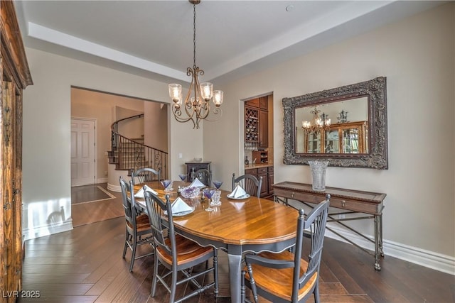 79 Rezzonico Dr, Henderson, NV 89011 - dining space featuring a chandelier, stairs, dark wood-style floors, baseboards, and a tray ceiling