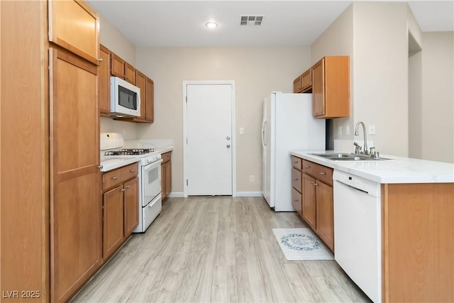 7486 River Dove Ct, Las Vegas, NV 89139 - kitchen featuring white appliances, light wood finished floors, light countertops, brown cabinetry, and a peninsula