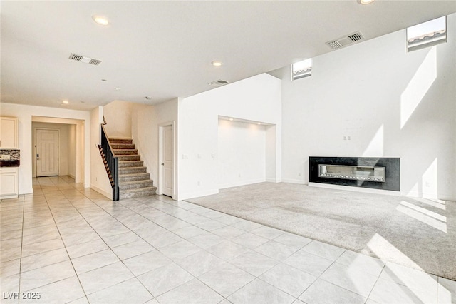 9993 Birch Knoll Ave, Las Vegas, NV 89166 - unfurnished living room featuring stairs, a glass covered fireplace, light carpet, recessed lighting, and light tile patterned floors