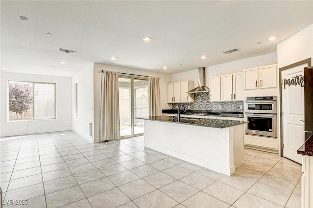 9993 Birch Knoll Ave, Las Vegas, NV 89166 - kitchen featuring wall chimney exhaust hood, stainless steel appliances, a sink, a kitchen island with sink, and light tile patterned floors