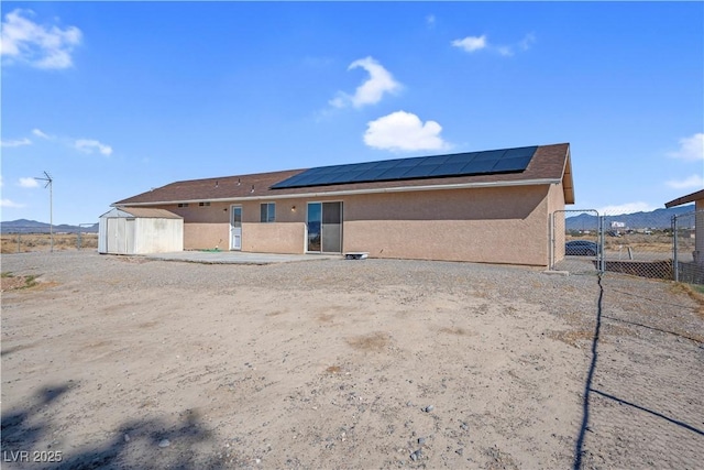 2831 Goldrush St, Pahrump, NV 89048 - rear view of house featuring an outdoor structure, stucco siding, a shed, fence, and a gate