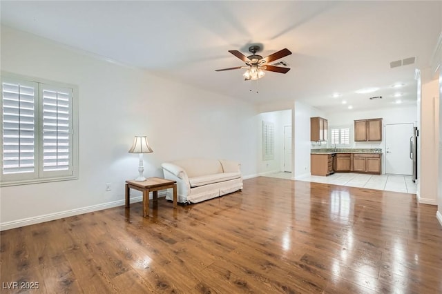 2409 Garganey Ave, North Las Vegas, NV 89084 - unfurnished living room with light wood finished floors, a ceiling fan, and baseboards