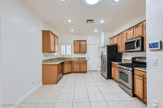 2409 Garganey Ave, North Las Vegas, NV 89084 - kitchen featuring appliances with stainless steel finishes, ornamental molding, brown cabinetry, light tile patterned floors, and a sink