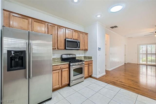 2409 Garganey Ave, North Las Vegas, NV 89084 - kitchen with stainless steel appliances, light tile patterned floors, light stone counters, open floor plan, and brown cabinets