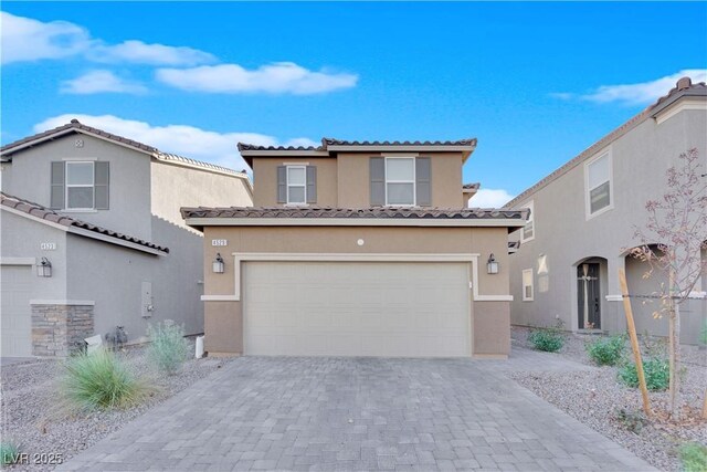 mediterranean / spanish home featuring decorative driveway, a tiled roof, stucco siding, and a garage