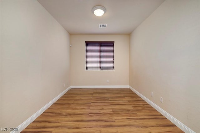 spare room featuring visible vents, light wood-style floors, and baseboards
