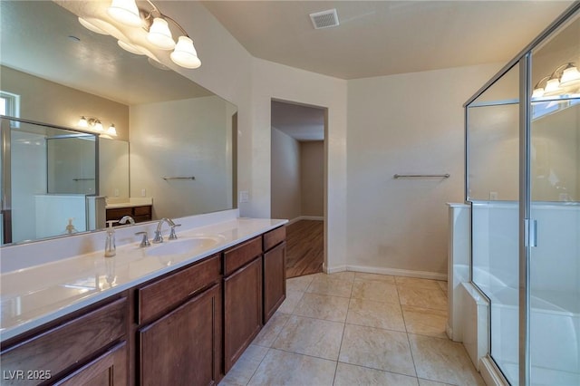 bathroom featuring vanity, baseboards, a stall shower, and visible vents
