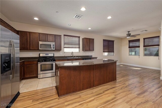 kitchen featuring a kitchen island, visible vents, a sink, light wood-style floors, and stainless steel appliances