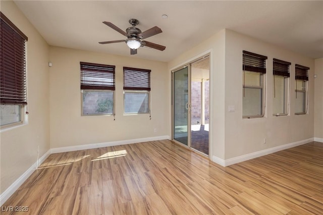 empty room featuring a healthy amount of sunlight, baseboards, ceiling fan, and light wood finished floors