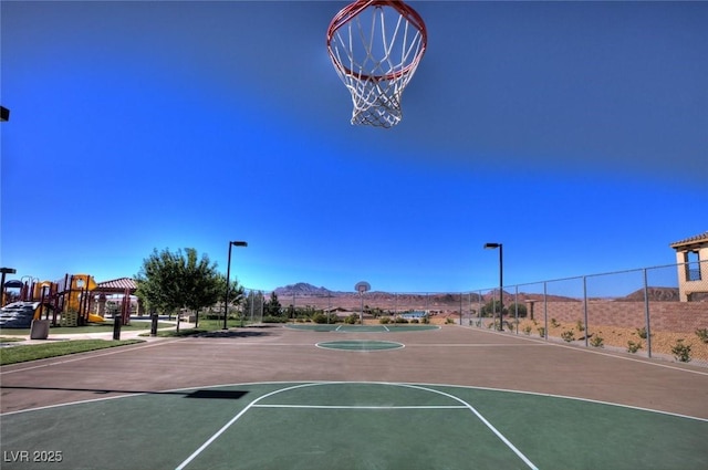 view of basketball court featuring community basketball court, fence, and a mountain view