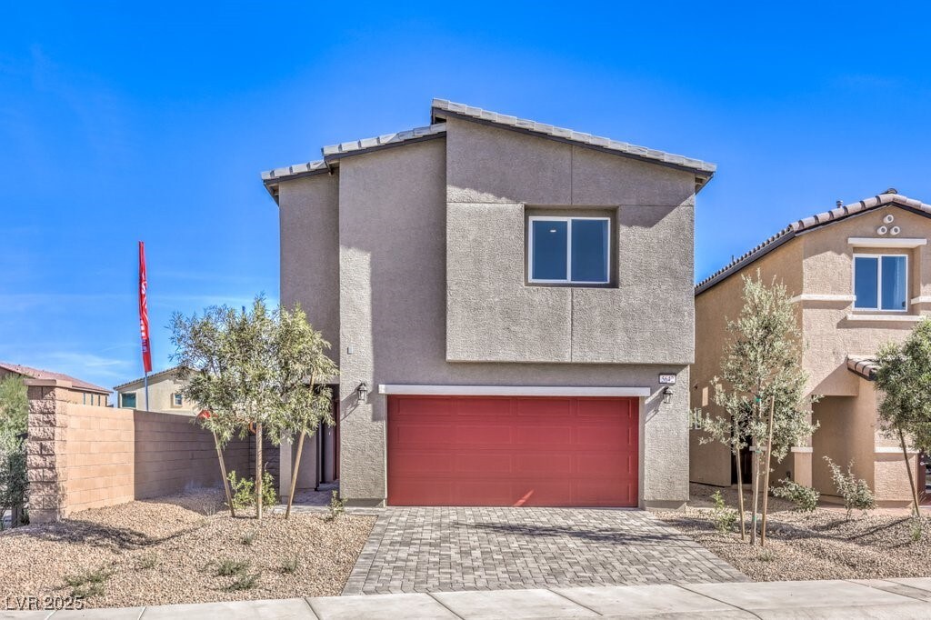 view of front facade featuring a garage, decorative driveway, stucco siding, and fence