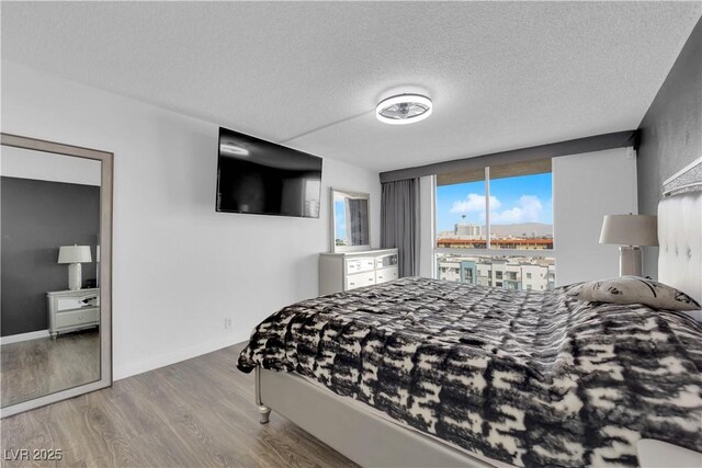 bedroom with baseboards, a textured ceiling, and wood finished floors
