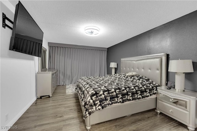 bedroom featuring wood finished floors, a textured wall, and a textured ceiling